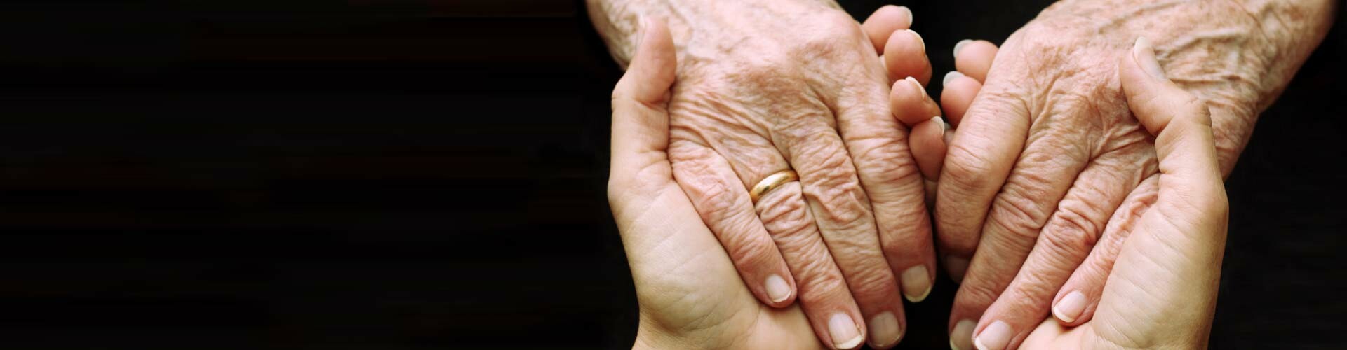 Eine junge und eine alte Person reichen sich die Hände