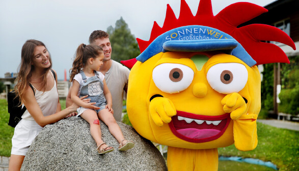 Mutter, Vater und Tochter mit dem SONNENWELT-Maskottchen Solarix