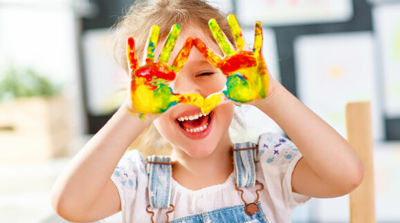 Kind mit Fingerfarben an den Händen