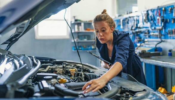 Mechanikerin &uuml;berpr&uuml;ft Motorraum eines Autos