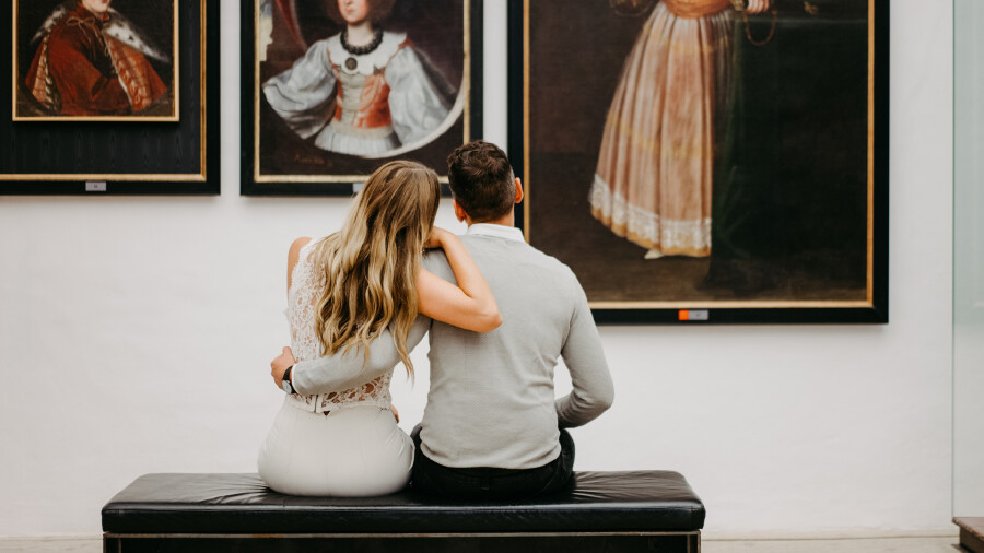 Paar sitzt auf Bank und betrachtet Gemälde