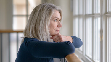 Frau blickt nachdenklich aus dem Fenster