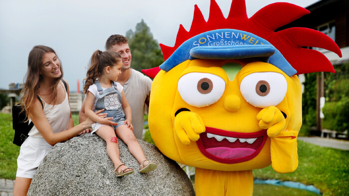 Mutter, Vater und Tochter mit dem SONNENWELT-Maskottchen Solarix