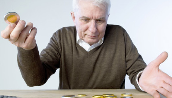 Alter Mann hält Münze in der Hand und schaut auf weitere Münzen die am Tisch liegen. © stock4you, Fotolia.com