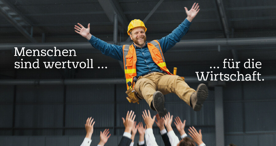 Ein grinsender Bauarbeiter wird von einer Gruppe von Menschen in die Luft geworfen. Dabei steht der Text "Menschen sind wertvoll f&uuml;r die Wirtschaft."