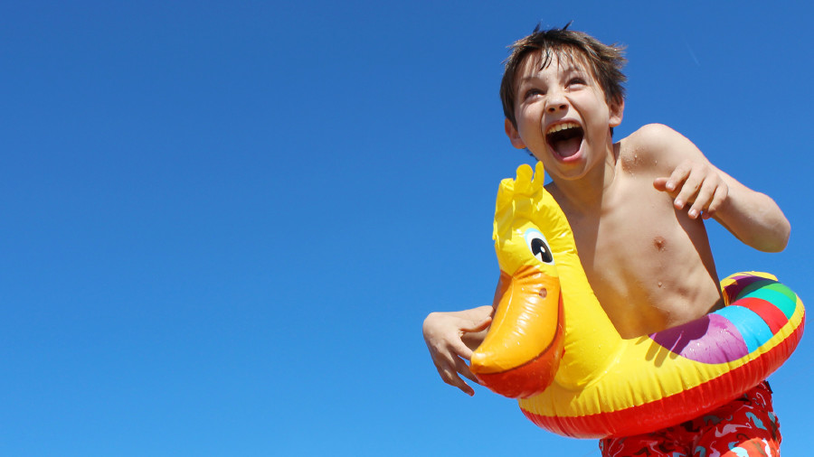 Bub mit Schwimmreifen © Natallia Vintsik , Adobe Stock Lachender Bub am Meer mit Schwimmreifen © Natallia Vintsik , Adobe Stock