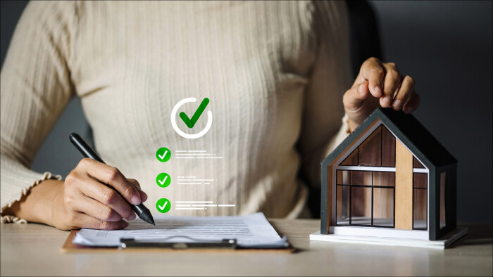 Frau mit Stift, Checkliste und Hausmodell